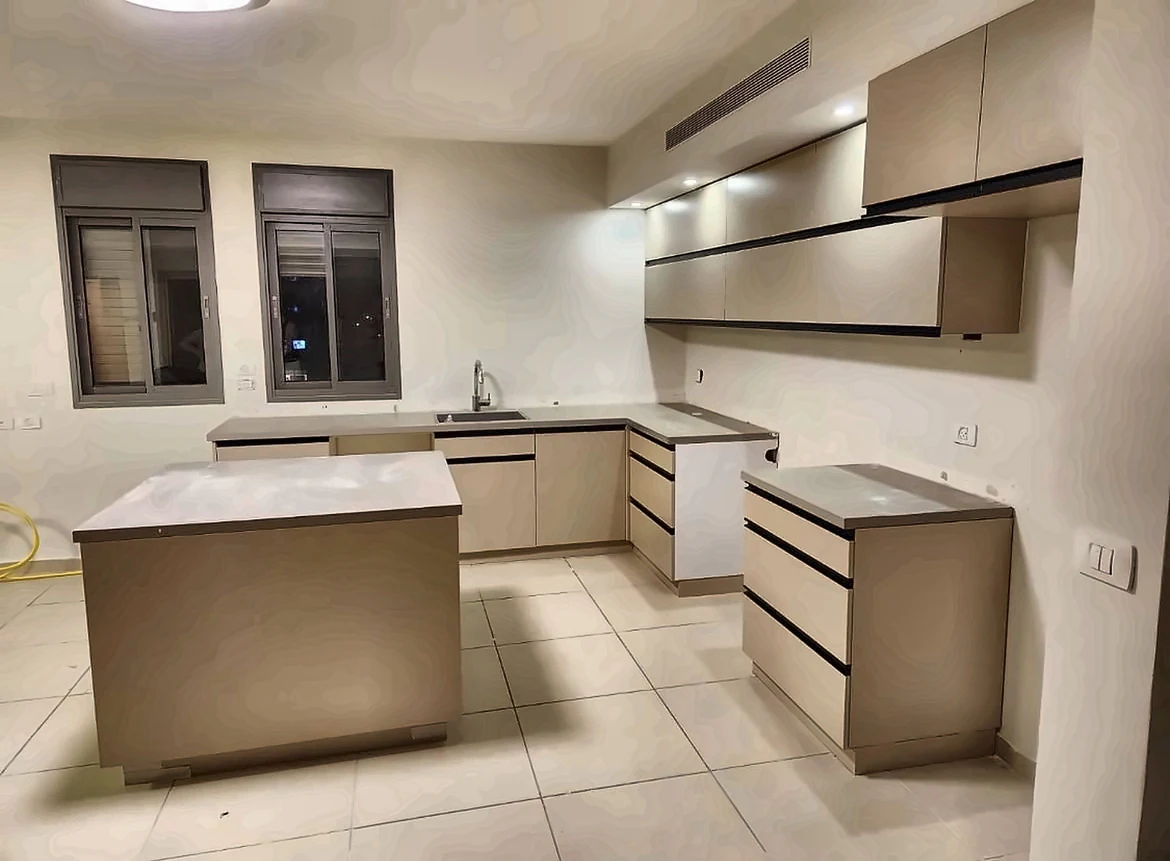 מטבח בגוון שמנת עם פסי ידיות שחורים, משטח אפור ואי מרכזי